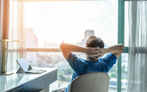Man looking out office window with hands behind his back